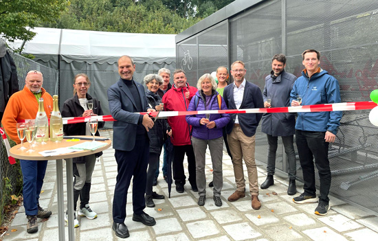 Menschen, die vor der neuen Sammelschlie�anlage f�r R�der stehen. Der Oberb�rgermeister schneidet zur Er�ffnung ein Band durch.